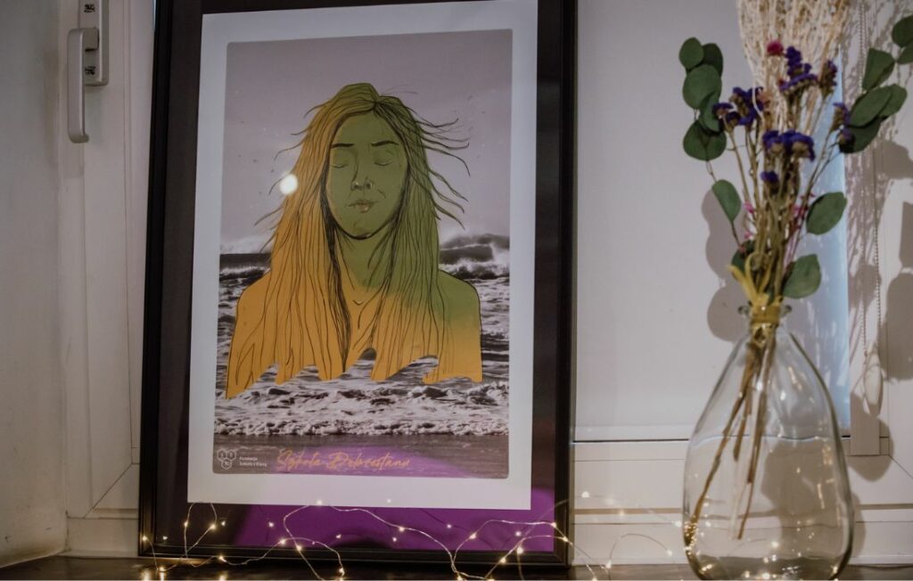 Obraz w ramie, przedstawiający kobietę. Obraz stoi na parapecie, obok wazon z kwiatami